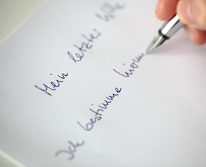 Ein Blatt Papier, auf das gerade jemand "Mein letzter Wille" schreibt.