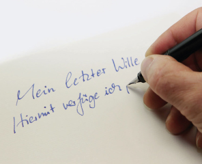 Eine Hand schreibt mit Füller: "Mein letzter Wille. Hiermit verfüge ich,..."